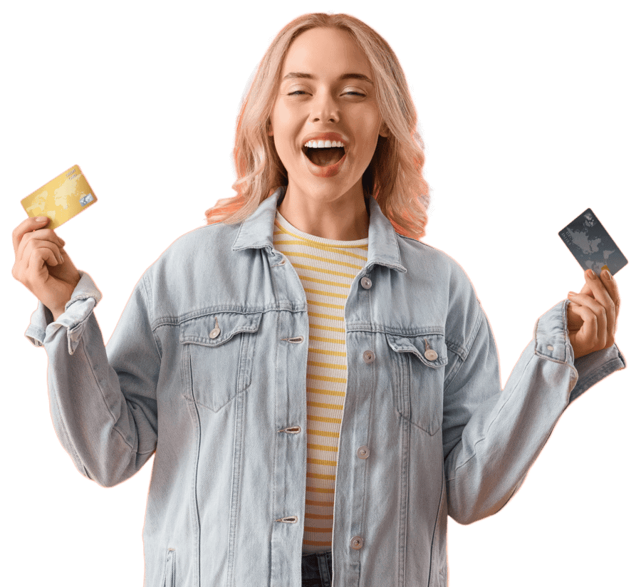 Woman wearing a light denim jacket and yellow striped shirt smiles while holding two credit cards, one in each hand, against a plain background—ready to repair her finances like a skilled attorney.